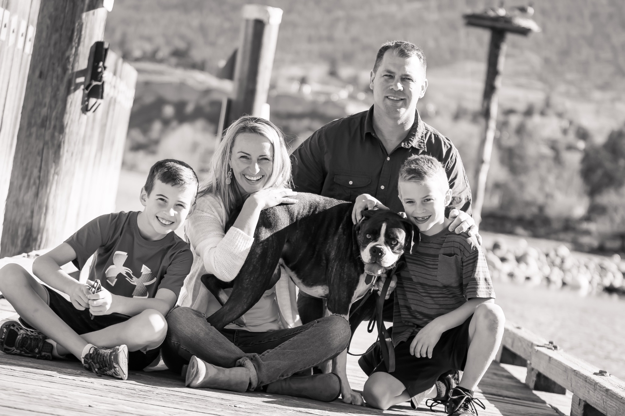 Black-and-white outdoor family portrait with two parents, two children and their dog