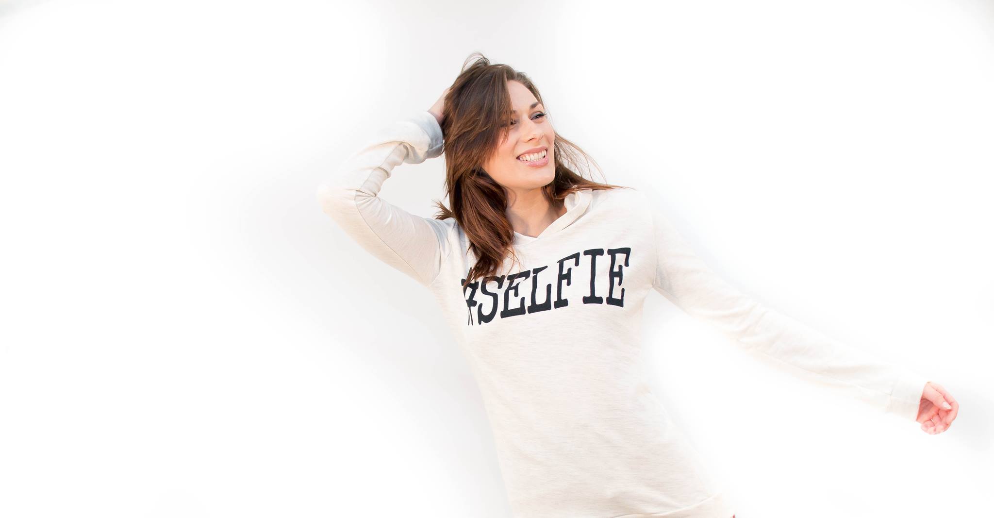 Bright high-key lifestyle portrait of a smiling woman in a white sweatshirt