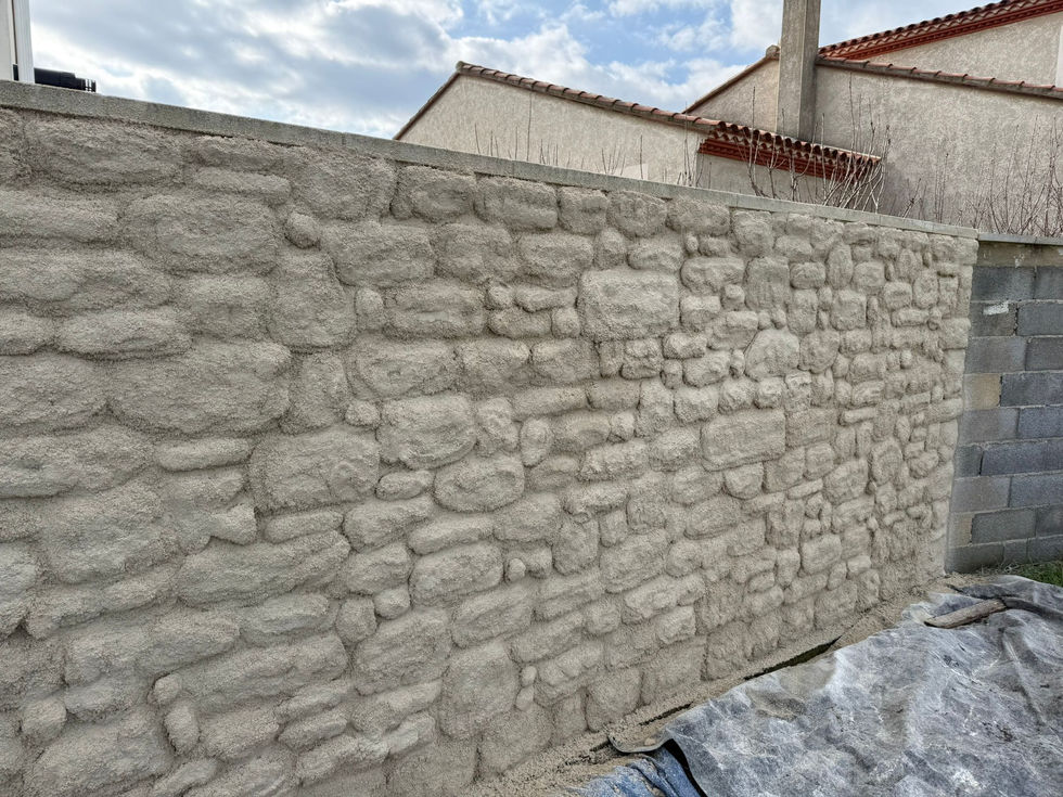 Détail de fausse pierre bâtie en enduit à la chaux naturelle pour mur de clôture dans le Gard