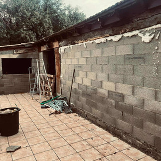 Mur extérieur en parpaings bruts avant rénovation, terrasse carrelée et structure existante avant réalisation d’un parement en imitation pierre par L’Artiste Pierres dans le Gard.