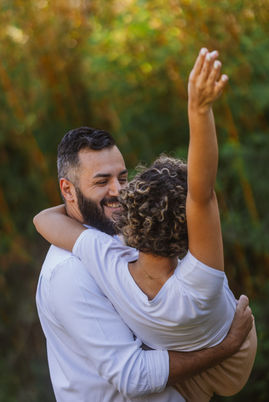 Casal feliz, posando na grama de pés descalços e roupas claras, celebrando seu pré-casamento