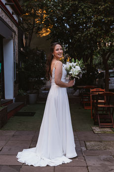 Mulher sorri para foto no dia do seu casamento em frente ao verde durante o dia