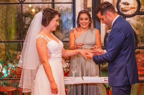 Casal de noivos felizes se olham enquanto trocam as alianças de casamento