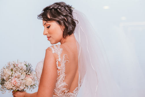 Noiva de costas com vestido em renda segurando o buquê