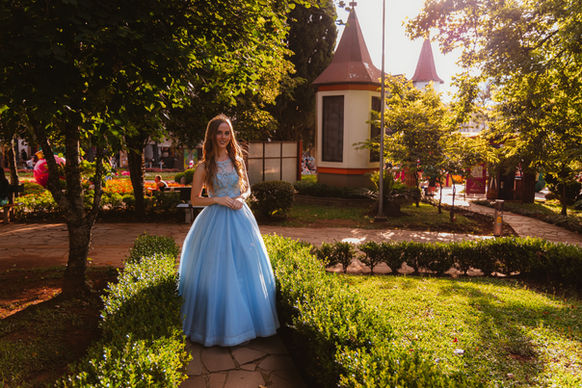 Moça jovem sorrindo para foto em meio à praça em Nova Petrópolis com seu vestido de debutante