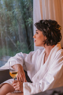 Noiva observa pela janela com uma taça na mão enquanto se prepara para o seu casamento