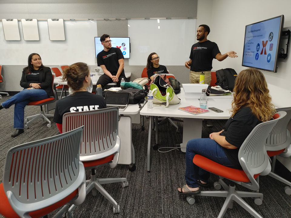 A member of the TEDxBellarmineU core team sit and watch a fellow member present social media strategies to those in attendance.  