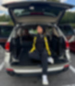 Woman in photography gear sitting in an open SUV trunk.