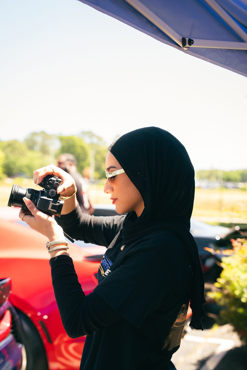 Woman in a black hijab practicing photography outdoors.