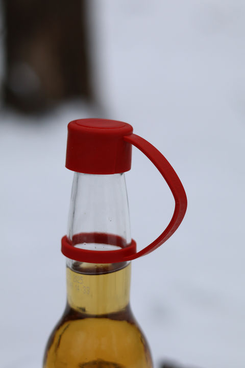Closeup of Swig Essentials reusable bottle cap on a beer bottle wiht snow in the background