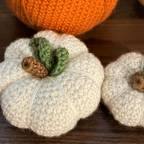 two white crocheted pumpkins on a dark wooden surface, cozy handmade fall decor