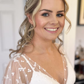 Smiling bride wearing natural makeup and a half-up haistyle with soft waves, captured at her wedding in Surrey 