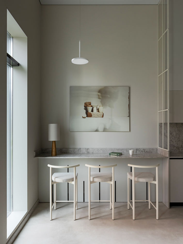 Minimalist café interior with sleek espresso machines, woven chairs, pendant lights, and neatly set tables.
