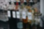 Five labeled bottles: fish sauce, soy sauce, vinegar, olive oil, cooking oil on a kitchen counter. Background shows a dish rack.