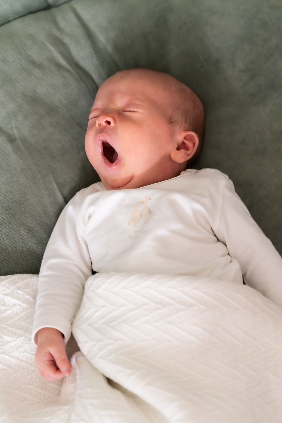 Baby die geeuwt en slaapt tijdens rustige newborn fotoshoot thuis