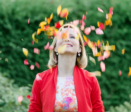 Eine Frau wirft Blumenblätter in die Höhe und schaut nach, sie ist freie Traurednerin