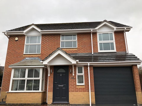 Front facing view of a large red brick family home with garage