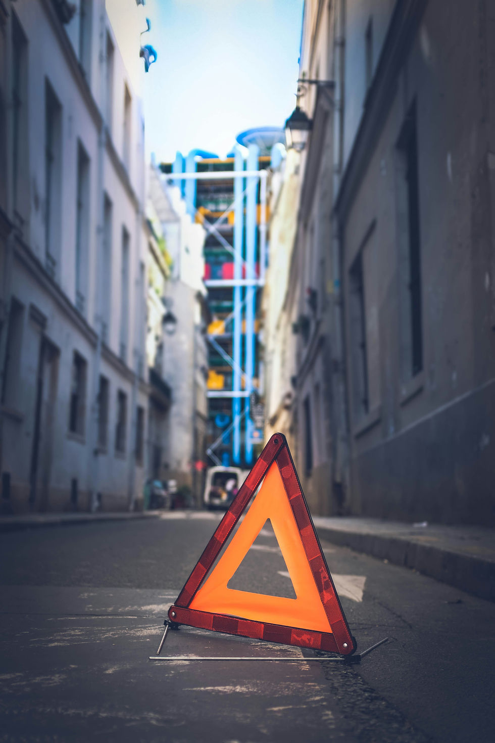 Un triangle de signalisation orange au milieu de la rue