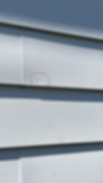 Hail damage on aluminum siding circled with chalk - TomKat Restoration