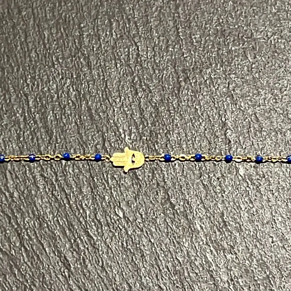 Miniatura: Vista frontal pulsera ajustable de acero dorado con Mano de Fátima y pequeñas cuentas azul sobre cadena fina.