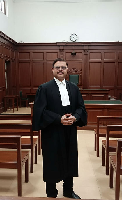 Professional lawyer seated at a wooden desk in a law office, wearing a black suit and white band, with law books, a gavel.