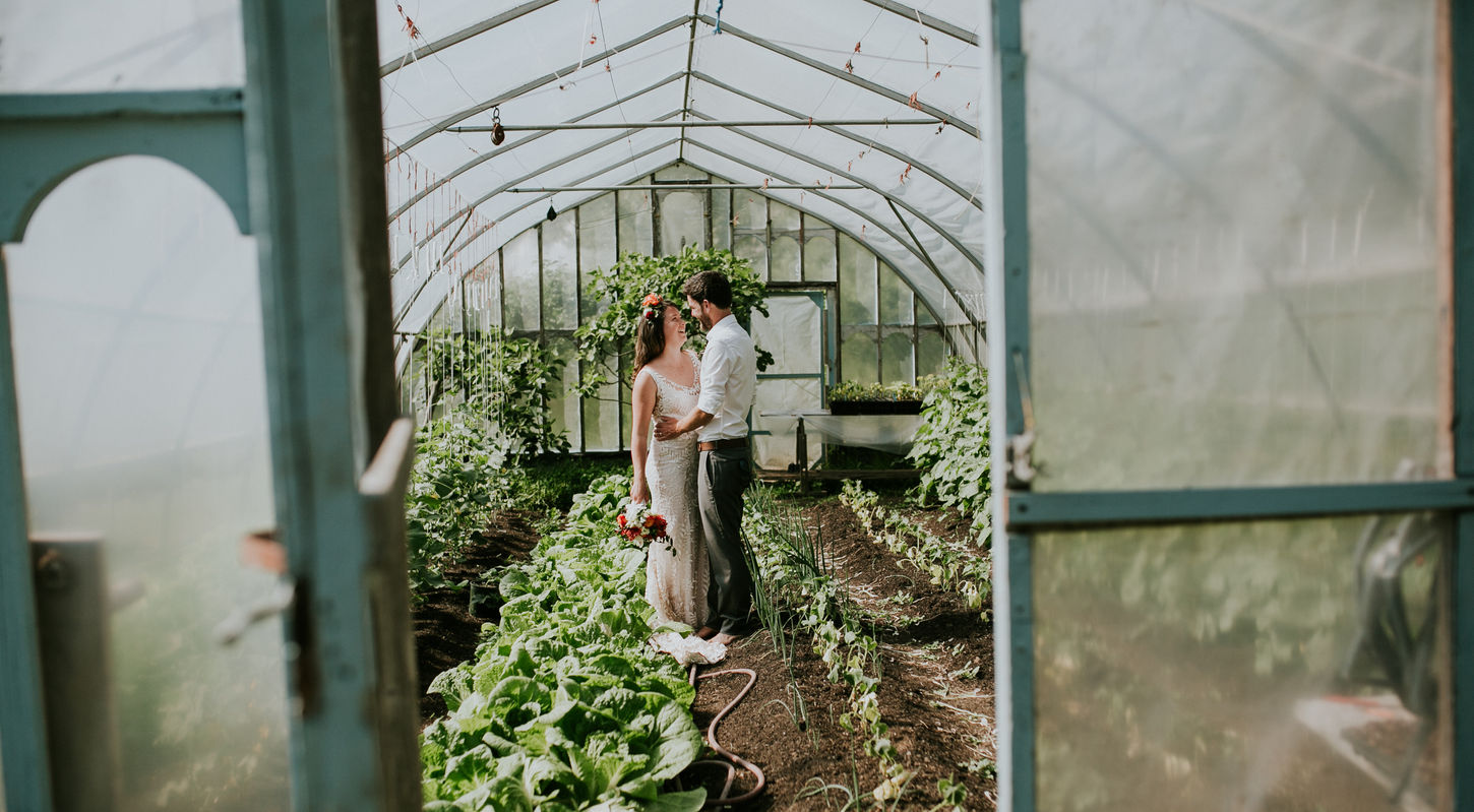 A couple sneaks a kiss in a greenhouse oasis