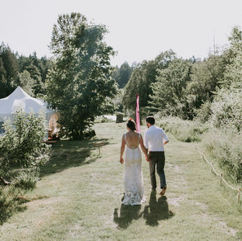 A couple walking down a grassy aisle with plants growing on either side