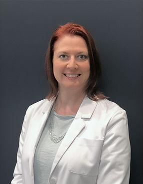 Smiling woman with reddish-brown hair in a white lab coat