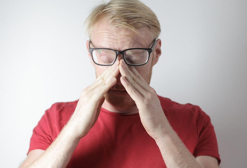 Man in a red shirt with glasses rubs his dry eyes
