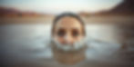 image of a woman's face coming out of the water in a desert with eyes showing above the wa