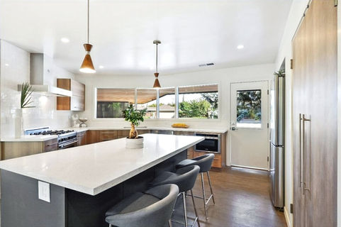 This mid-century modern kitchen boasts clean lines, natural materials, and neutral colors, creating a warm and inviting atmosphere. The eat-in island adds functionality, making it perfect for cooking and socializing. This kitchen is both on-trend and timeless, with a sleek and minimalist design that adds a touch of elegance.
