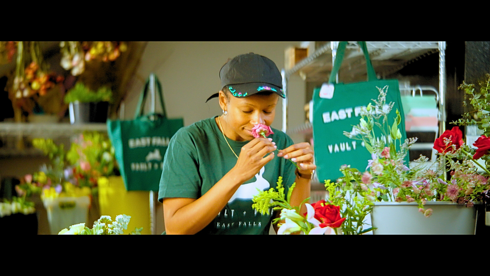 Woman with a cap gently smelling a pink flower