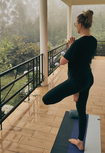 Frauke steht in der Baum-Haltung auf einem Balkon und blickt ruhig in die Landschaft