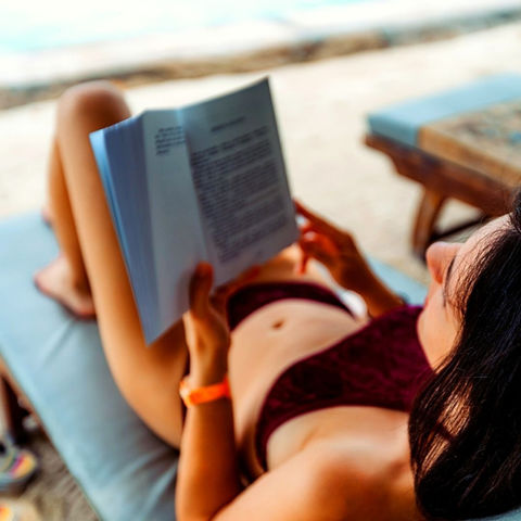 Lady reading a book on the beach