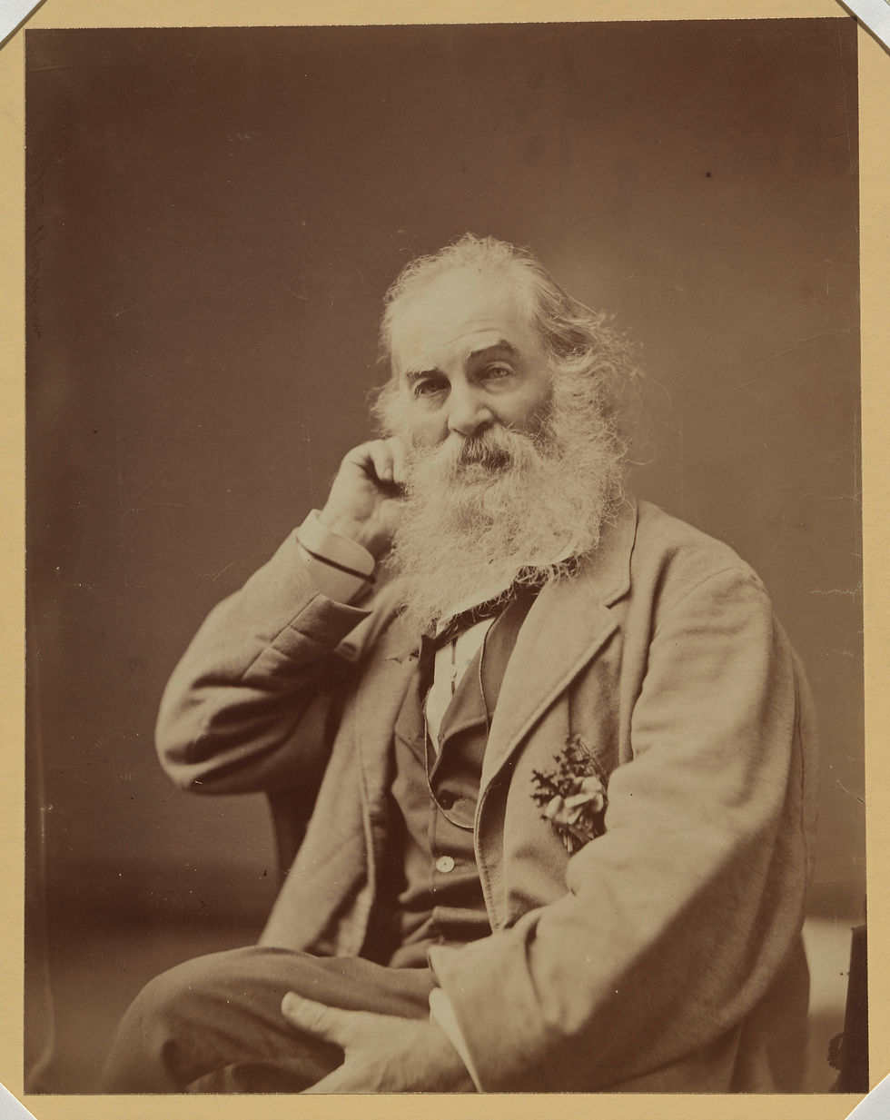 A sepia-toned seated portrait photograph depicting bearded white man Walt Whitman, who is dressed in formal attire and holding his right hand up behind his left ear.