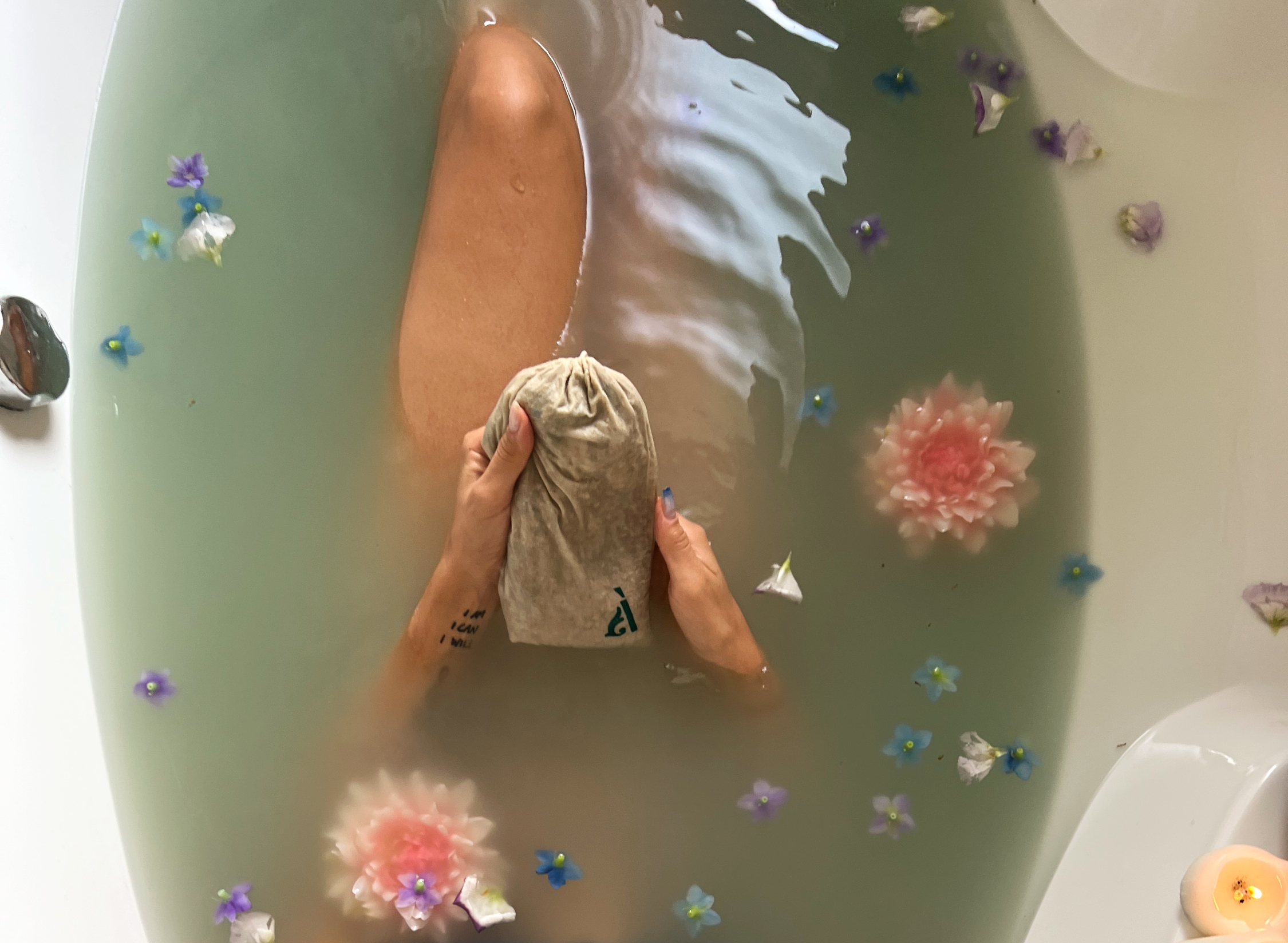 Close-up view of candles and essential oils on a wooden tray near a bathtub