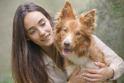 A young woman holding her tan and white border collie