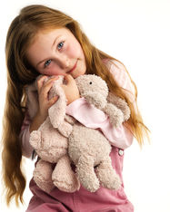 An expressive portrait of a seven year old girl hugging her bunny plush toys