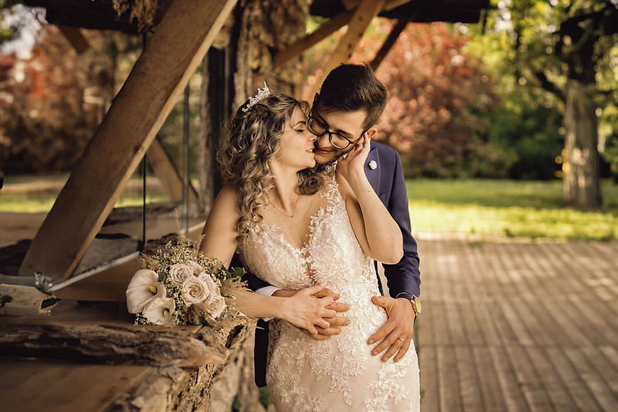 Due sposi abbracciati sotto pergolato nel verde, fotografo per matrimonio