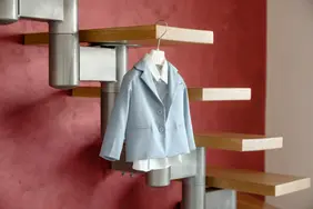 Abito azzurro da battesimo appeso alla scala a Novara.