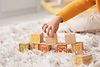 Petite fille jouant avec des cubes en bois sur le tapis à la maison, en gros plan.jpg