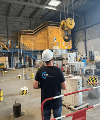 Employé de l'entreprise A2L Luxembourg manœuvrant une grue dans un entrepôt.