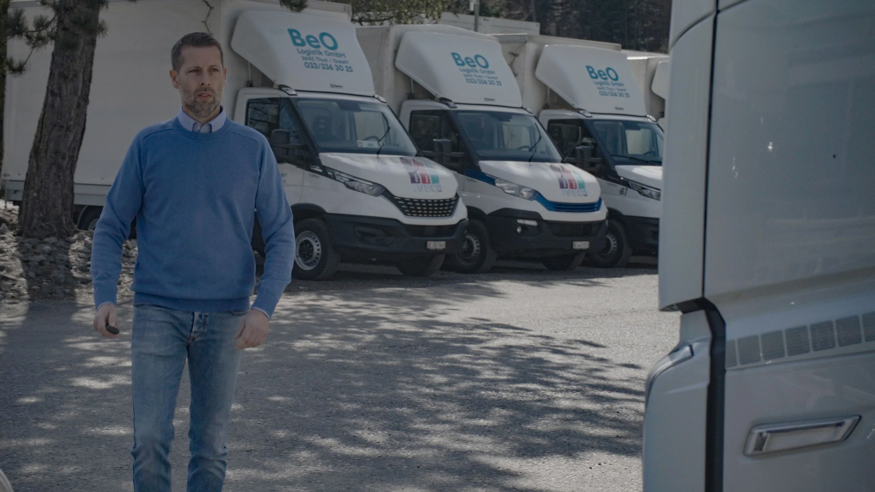 Person mit blauem Pullover, welcher vor Lieferungswagen mit der Aufschrift BeO Logistik herläuft.