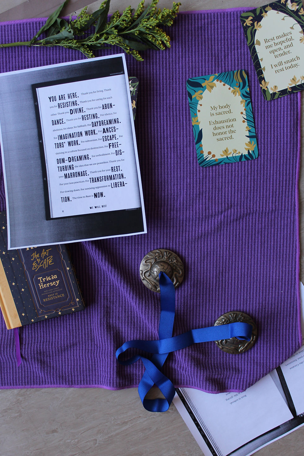 A flat lay of ritual objects arranged on a purple cloth, including cards, books, ribbon, and small ceremonial items.