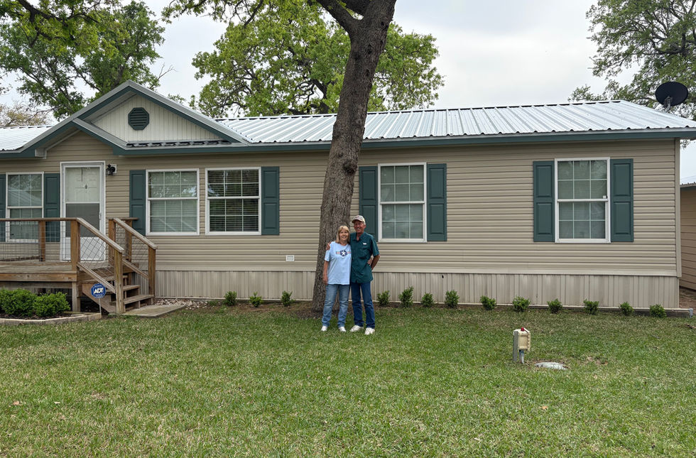 A happy couple in front of a newly repaired house roofing.