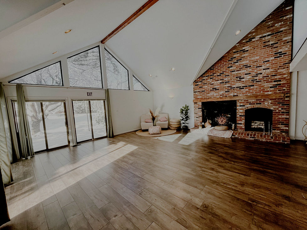 Bright, empty room with vaulted ceiling, brick fireplace, and wooden floor.