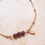 Miniature : Bracelet rouge grenat avec pierres naturelles, rondes et facettées, montées sur une chaînette en acier inoxydable doré.