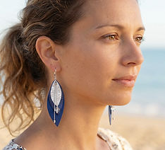 Femme portant des boucles d’oreilles en cuir ivoire fabriquées à Paris, lég