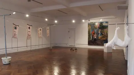 an empty room with a painting on the wall and a few flags hanging from the ceiling
