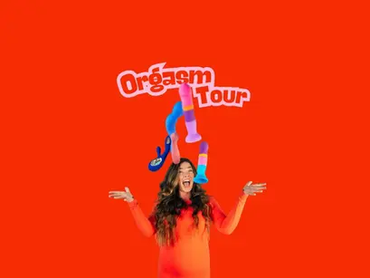 A woman in an orange top excitedly gestures under colorful toys against a bright red background with "Orgasm Tour" text overhead.